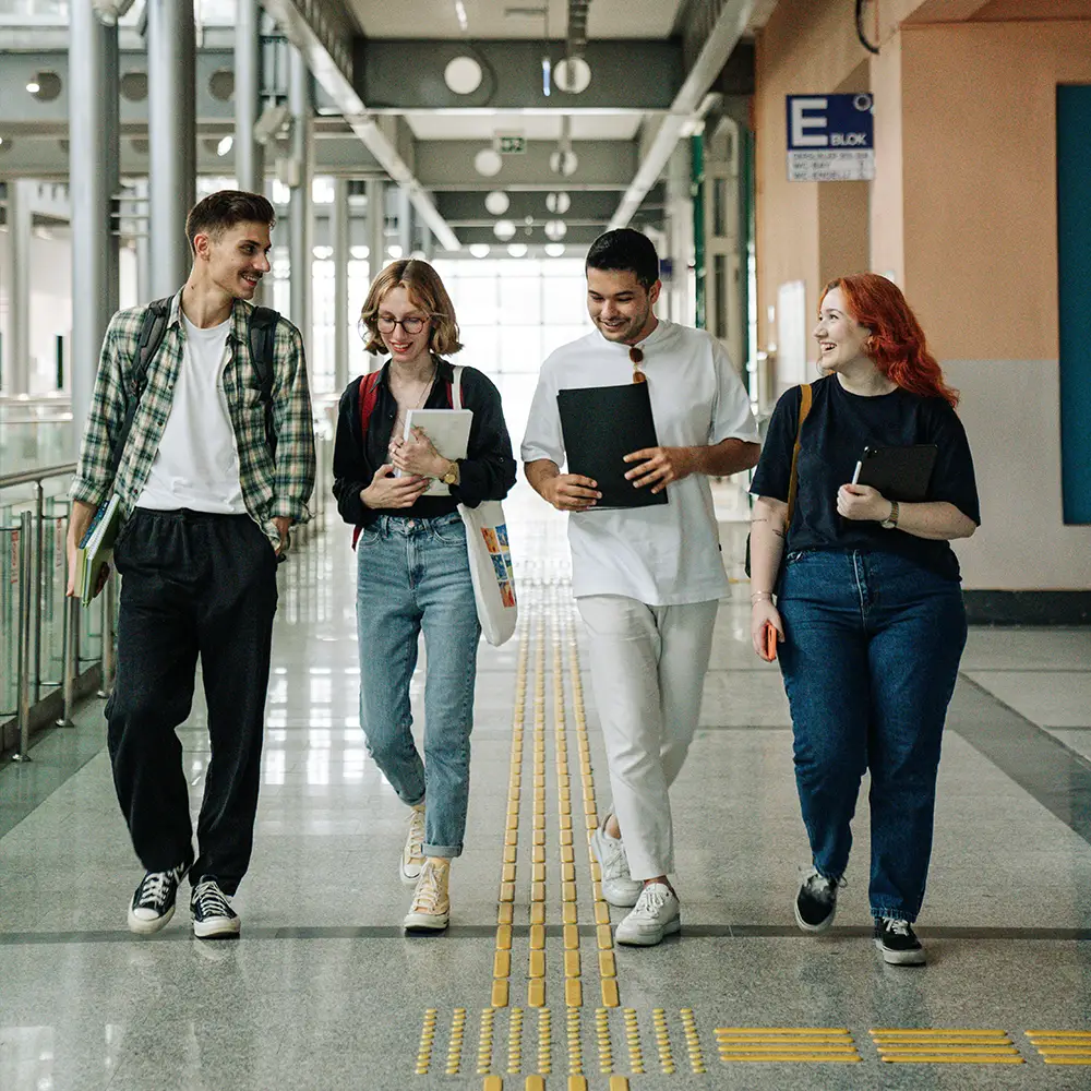 Quatre jeunes marchent ensemble avec leurs affaires de cours
